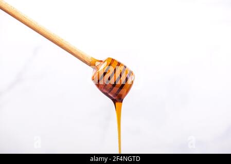 Honey dripping from a wooden spoon for honey on a white background Stock Photo