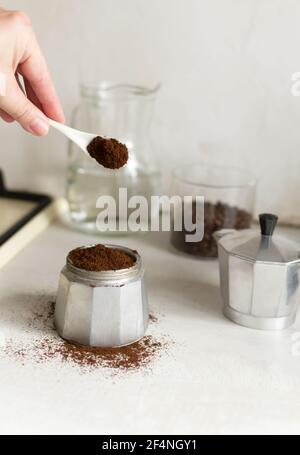 The process of making coffee at home. Coffee is poured into the geyser coffee maker in the home kitchen. Vertical orientation. Stock Photo