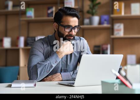 Serious indian business man working or studying on laptop computer. Stock Photo