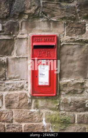 Red Royal Mail letter post box in old historic dry stone wall rural location ER logo and collection times - Editorial Stock Photo