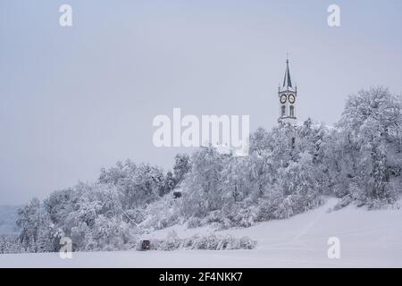 Church like a castle in a fairytale on snow caped hill with frosty forest. Church of Rein at Ruefenach in wintertime, canton Aargau in Switzerland. Stock Photo