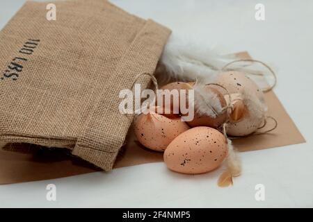 Brown easter eggs with feathers with a cardboard box on a table Stock Photo