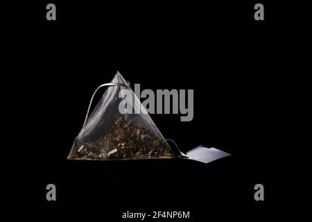 Floral tea bag with white label isolated on black background. Tea pyramid close up Stock Photo