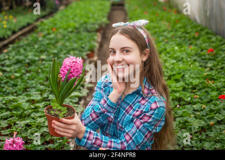 happy teen girl florist care pot plants in greenhouse, summer Stock Photo