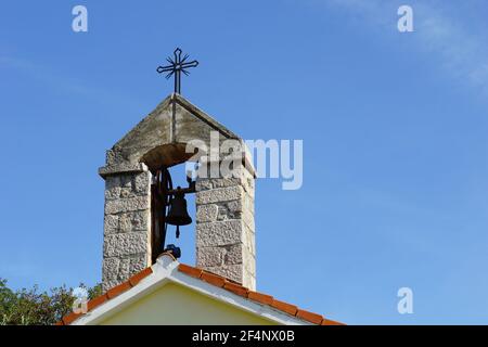 Picturesque small bell tower made of stone. Bell tower of the old church in front of the blue sky Stock Photo