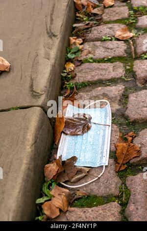 Wet medical mask dropped on the street, pandemic unsustainable rubbish left by the pavement. Dirty face covering carelesly put on the ground in Oxford Stock Photo