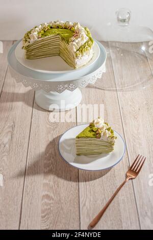 Matcha Mille Crepe Cake Presented On A Cake Holder With A Slice On A Plate Stock Photo