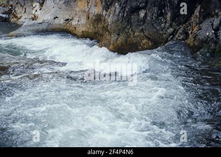 Powerful mountain creek after winter snow is molten, cascading over wet rocks of a narrow canyon Stock Photo