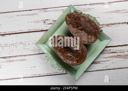 Two halves of chocolate Easter egg, on a small old tray (with copy space). Stock Photo