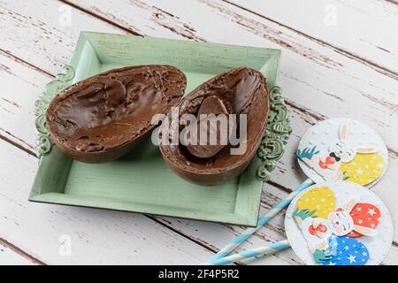 Two halves of chocolate Easter egg, on a small old tray. Stuffed with small choclolates. Stock Photo