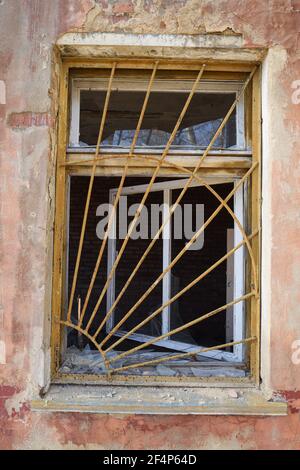 Rusty iron security grille on broken window in old brick ruined abandoned house vertical Stock Photo