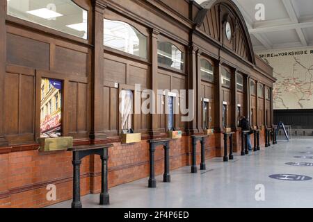 Manchester Victoria Railway Station wooden fronted ticket office with a single passenger at window during national lockdown in England. Stock Photo