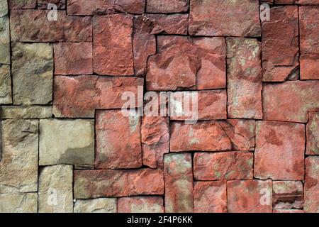 Wall of square stones of different sizes. Rectangular tiles of different sizes made of natural red stone Stock Photo