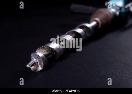 An old hand drill with a large drill bit. Tools for working in a carpentry workshop. Dark background. Stock Photo