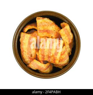 Bowl of bacon-flavored puffed wheat chips. Bacon Chips. Delicious bacon snacks isolated on white background. Pelleted salted snack bacon. Smoked bacon Stock Photo