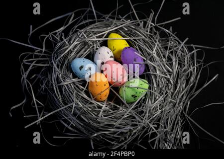 Colorful eggs in a handmade basket on black background. Creative eastern background Stock Photo