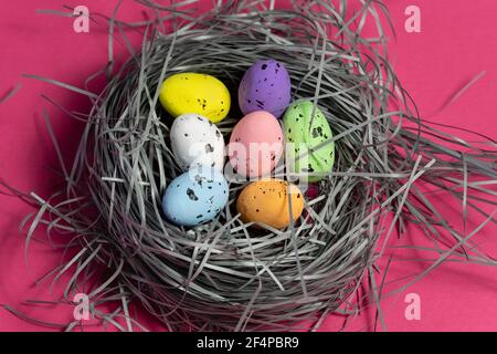 Colorful eggs in a handmade basket on pink background. Creative eastern background Stock Photo