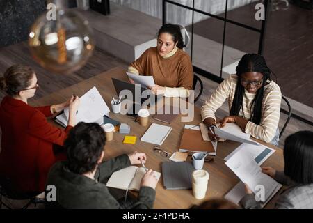 High angle view at diverse group of business people meeting at table in graphic office interior, copy space Stock Photo
