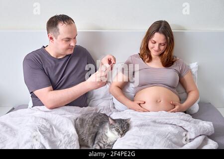 A man takes a video and photo of a pregnant woman belly on a mobile phone Stock Photo