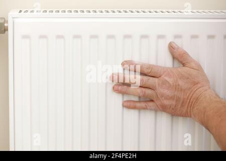 Man in work overalls using wrench while installing heating radiator in room. plumber installing heating system in apartment. Concept of radiator insta Stock Photo