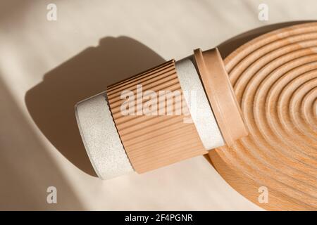 Reusable cup, biodegradable travel plastic coffee mug take away. Bamboo eco friendly cup on natural shadow beige background with wooden decor. Zero Stock Photo