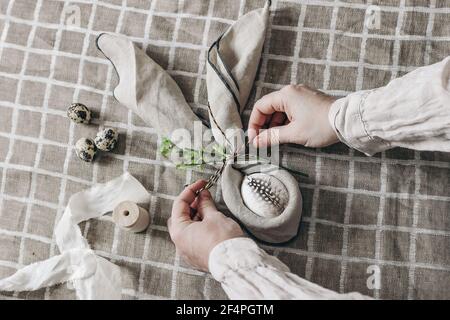 Closeup of womans hands folding napkins. Easter decorative table setting. Spring still life with quail and hen eggs. Beige linen table cloth Stock Photo