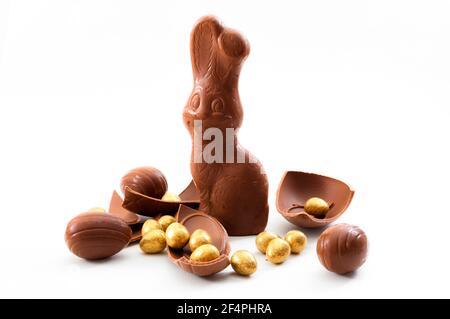 Passover, happy Easter and good Friday wishes concept with a chocolate bunny surrounded by pieces of chocolate eggs isolated on white background with Stock Photo
