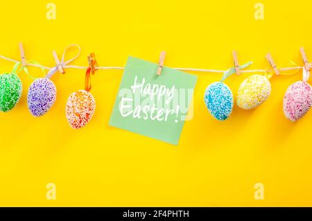 Christianity, Christian tradition concept with colorful Easter Eggs painted in various colors and decorated with white beads hanging on a string or ro Stock Photo