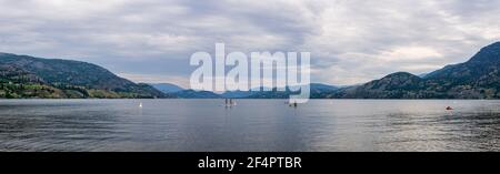 PENTICTON, CANADA - JULY 3, 2020: recreation time paddle boarding on scenic peaceful mountain lake panorama. Stock Photo