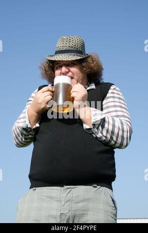 Funny fat guy is drinking beer. Stock Photo