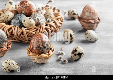 Easter composition - several marble eggs painted with natural dyes in a wicker nest and baskets. Stock Photo