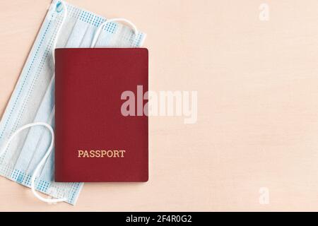 Safe travel during coronavirus pandemic concept. Protective medical mask and passport on the table, copyspace, flatlay. Stock Photo