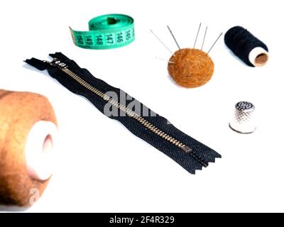 Knitted zipper and sewing accessories on a white background. Knitted zipper. Needles and threads. Sewing needles and threads. Tailors centimeter. Sewi Stock Photo