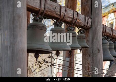 A group of bronze church bells hang in a row on a wooden beam Stock Photo