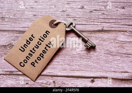 Text on tag with key on wooden table - Under construction property Stock Photo