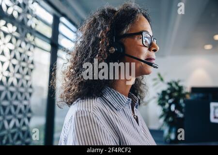 Closeup of a female business professional with headset at work. businesswoman looking busy working in office wearing a headset. Stock Photo