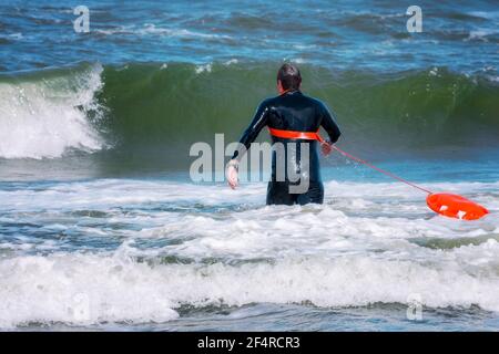 Lifeguard running to rescue a drowning person Stock Photo