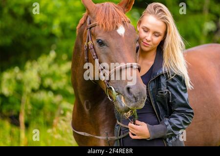 Beautiful young woman with her arabian horse in the field Stock Photo