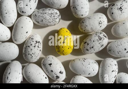 Little Easter white eggs and one yellow egg in the middle, with black elements, easter background Stock Photo