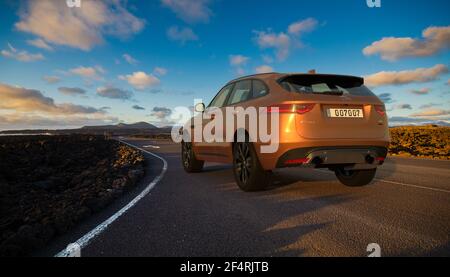 Jaguar F-Pace SUV on the road that runs through the volcanic landscape of Lanzarote Stock Photo
