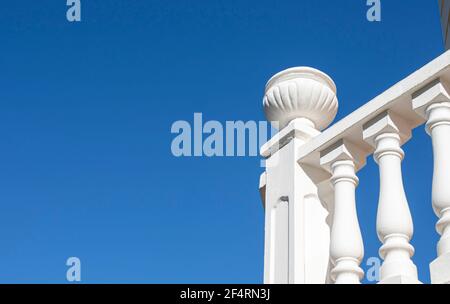 Sun-drenched white balustrade on blue sky background. Pillar finished with decorative planter made of concrete Stock Photo