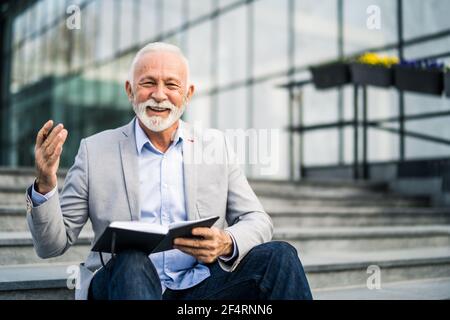 Happy senior businessman is writing his schedule. Stock Photo