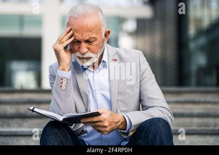 Senior businessman is pensive. He is thinking about his schedule. Stock Photo