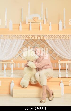 Senior woman with teddy bear at home Stock Photo