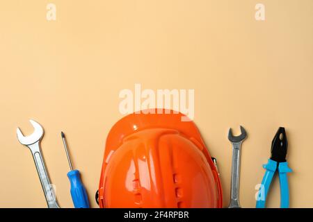 Hard hat and tools on beige background Stock Photo