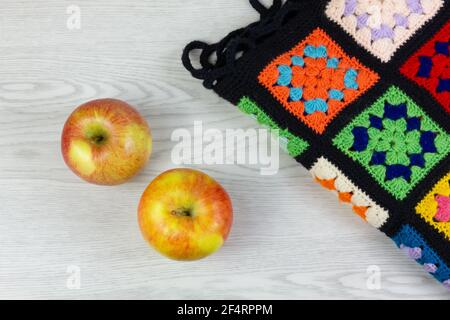 Above view of two yellow and red apples and a multicolor plaid blanket on a white wooden table Stock Photo
