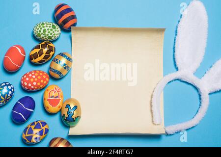Beautiful Easter photo with eggs and bunny ears with parchment paper for text.on a light minimalist blue background Stock Photo