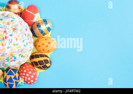 The layout of the Easter cake and multi-colored painted eggs on a light blue background in a minimalist style copy the space for text Stock Photo