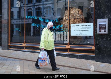 Leeds, UK. 23rd Mar, 2021. A shopper wearing as mask walks past the famous Harvey Nichols store that's displays a sign saying “We'll be back together soon” as stores prepare to re open in Leeds, UK on 3/23/2021. (Photo by Mark Cosgrove/News Images/Sipa USA) Credit: Sipa USA/Alamy Live News Stock Photo