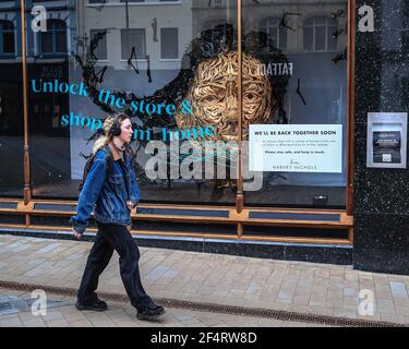 Leeds, UK. 23rd Mar, 2021. A shopper walks past the famous Harvey Nichols store that's displays a sign saying “We'll be back together soon” as stores prepare to re open in Leeds, UK on 3/23/2021. (Photo by Mark Cosgrove/News Images/Sipa USA) Credit: Sipa USA/Alamy Live News Stock Photo